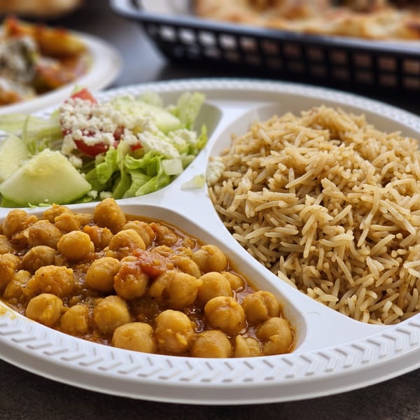 Chickpea curry, brown rice, and salad with feta cheese on a segmented white plate.
