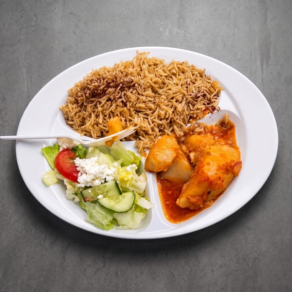 Chicken and potato stew, seasoned rice, and a fresh garden salad with feta on a divided plate.